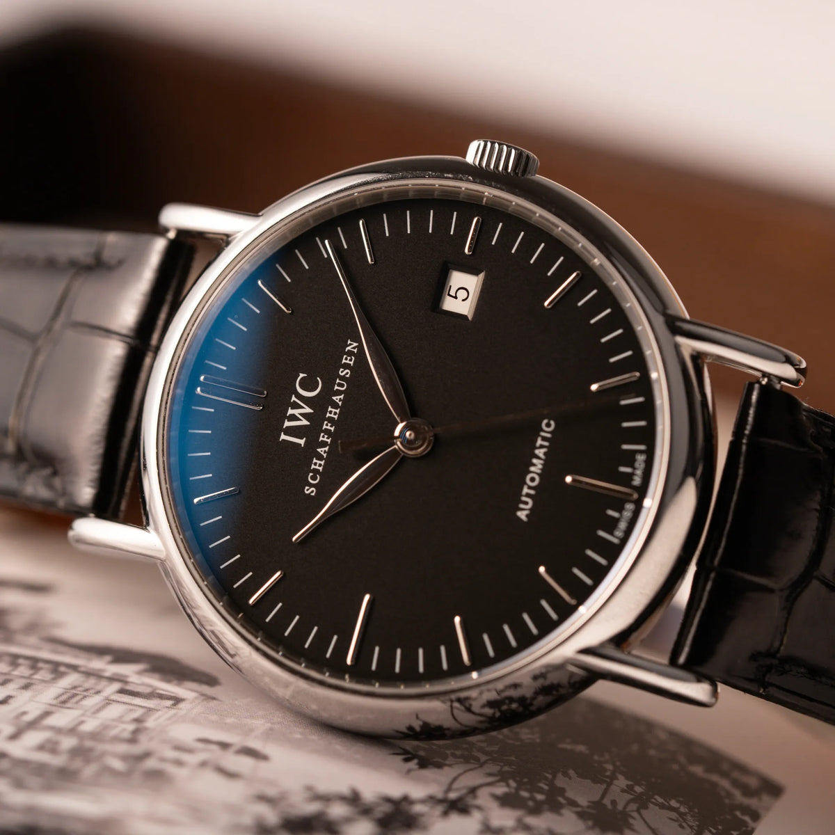 Detailaufnahme der IWC Portofino Automatik IW356305 Armbanduhr mit minimalistischen, schwarzem Zifferblatt mit Stichindizes am schwarzen Lederband