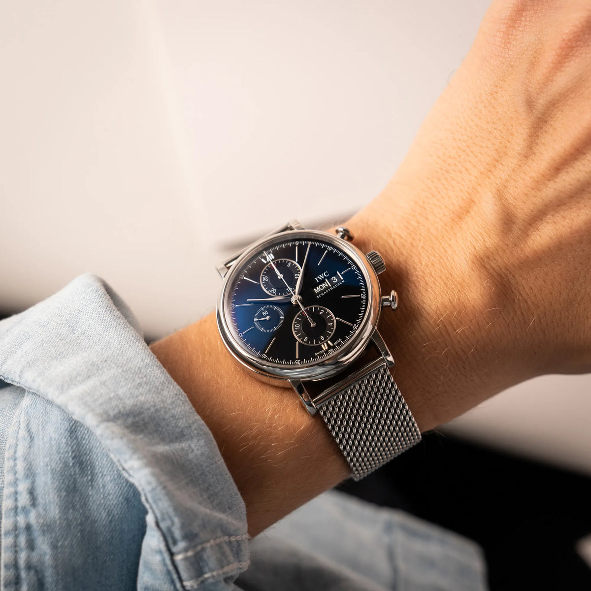 Mann präsentiert den IWC Portofino Chronograph der Referenz IW391002 mit schwarzem Zifferblatt an einem Mesh-Armband in die Kamera, während er die Uhr ans einem Hangelenk trägt