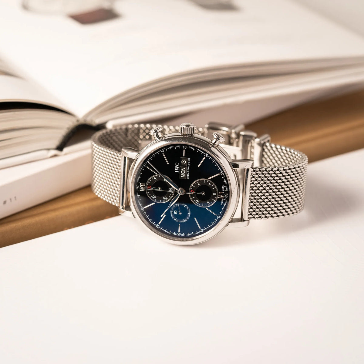 Produktfotografie des IWC Portofino Chronograph der Referenz IW391002 mit schwarzem Zifferblatt an einem Mesh-Armband