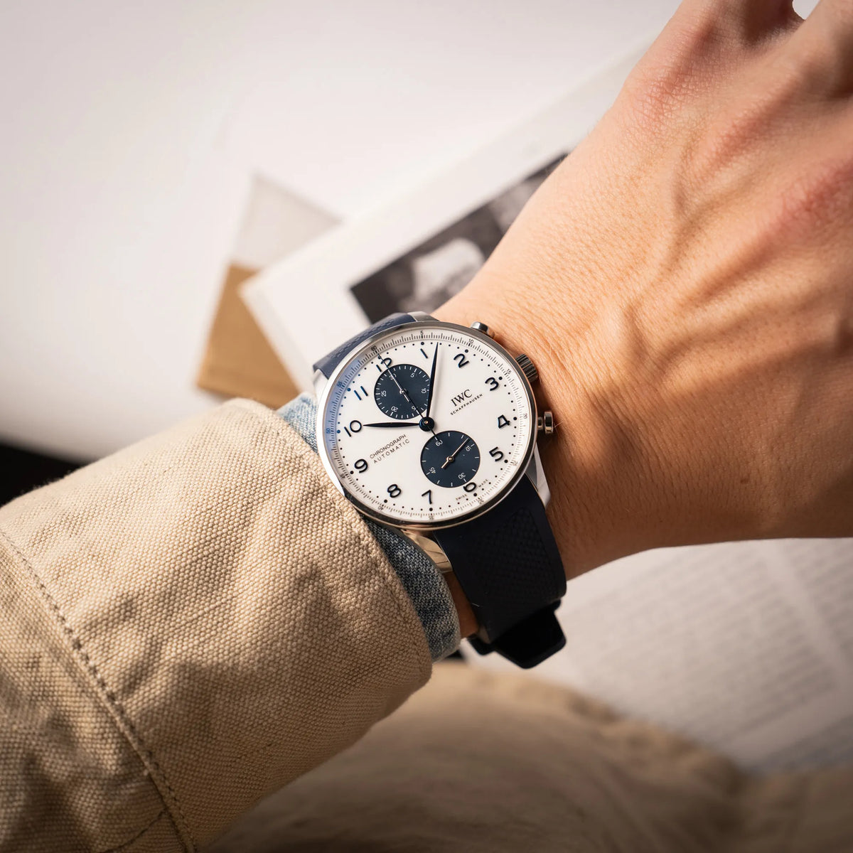 Mann trägt die IWC Portugieser Chronograph 41 der Referenz IW371620 mit weißem Zifferblatt und dunkelblauen Totalisatoren am passenden dunkelblauen Kautschukarmband für einen Wristshot