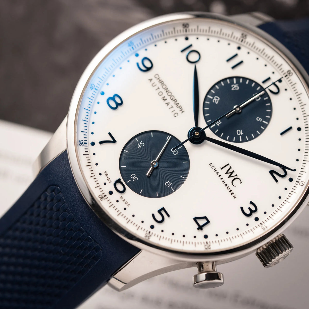 Detailaufnahme der IWC Portugieser Chronograph 41 der Referenz IW371620 mit weißem Zifferblatt und dunkelblauen Totalisatoren am passenden dunkelblauen Kautschukarmband
