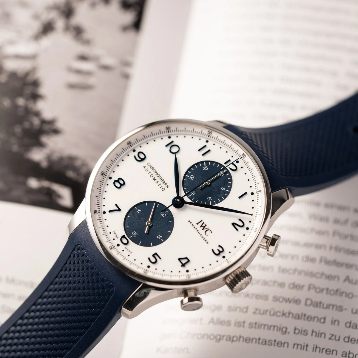 Produktfotografie als Titelbild für die IWC Portugieser Chronograph 41 der Referenz IW371620 mit weißem Zifferblatt und dunkelblauen Totalisatoren am passenden dunkelblauen Kautschukarmband