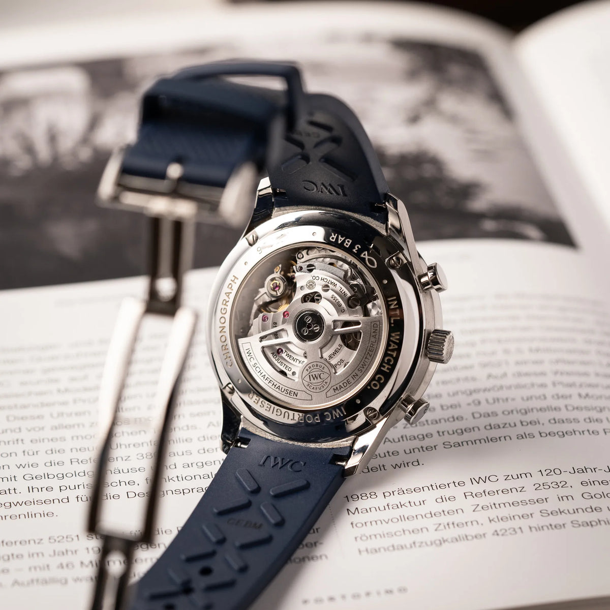 Produktfotografie zeigt den Gehäuseboden aus Sichtglas von der IWC Portugieser Chronograph 41 der Referenz IW371620 mit weißem Zifferblatt und dunkelblauen Totalisatoren am passenden dunkelblauen Kautschukarmband