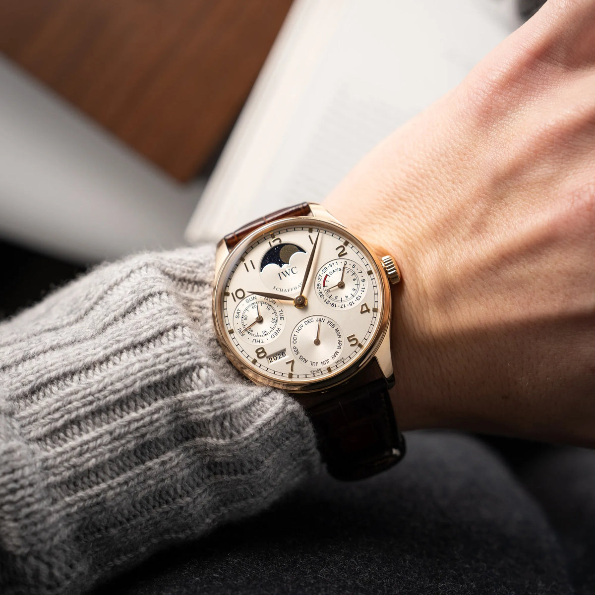 Mann trägt den Portugieser Ewiger Kalender IW502213 von IWC in einem 42mm-Rosegold-Gehäuse am braunem IWC Lederband mit einem sanften weißem Zifferblatt für einen Wristshot am Handgelenk