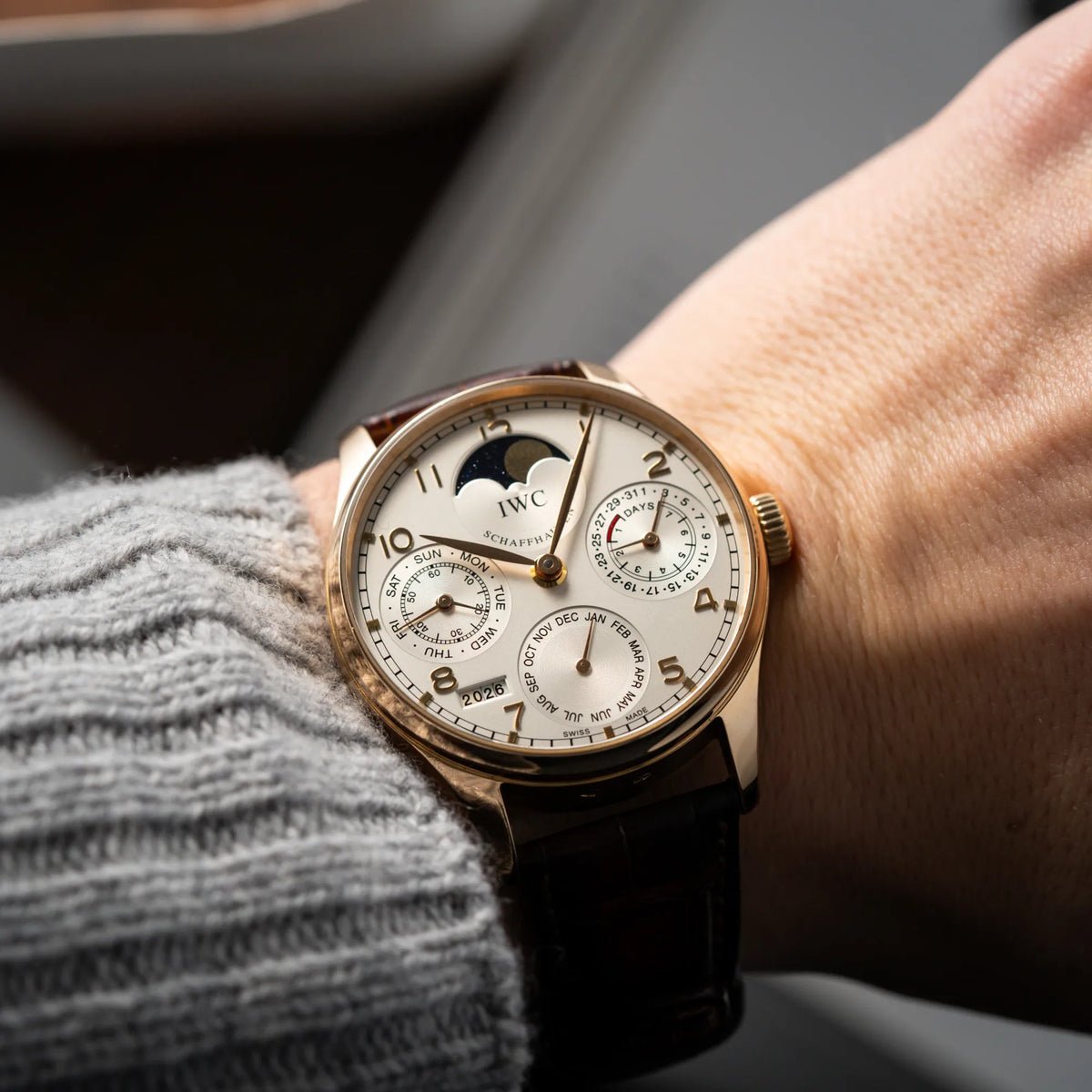 Mann trägt den Portugieser Ewiger Kalender IW502213 von IWC in einem 42mm-Rosegold-Gehäuse am braunem IWC Lederband mit einem sanften weißem Zifferblatt