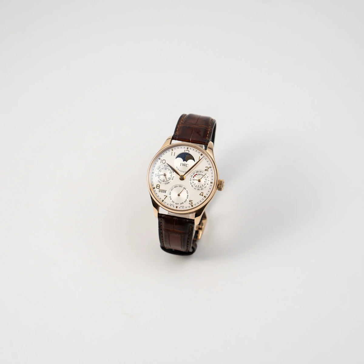 Leicht schräge Ansicht des Portugieser Ewiger Kalender IW502213 von IWC in einem 42mm-Rosegold-Gehäuse am braunem IWC Lederband mit einem sanften weißem Zifferblatt