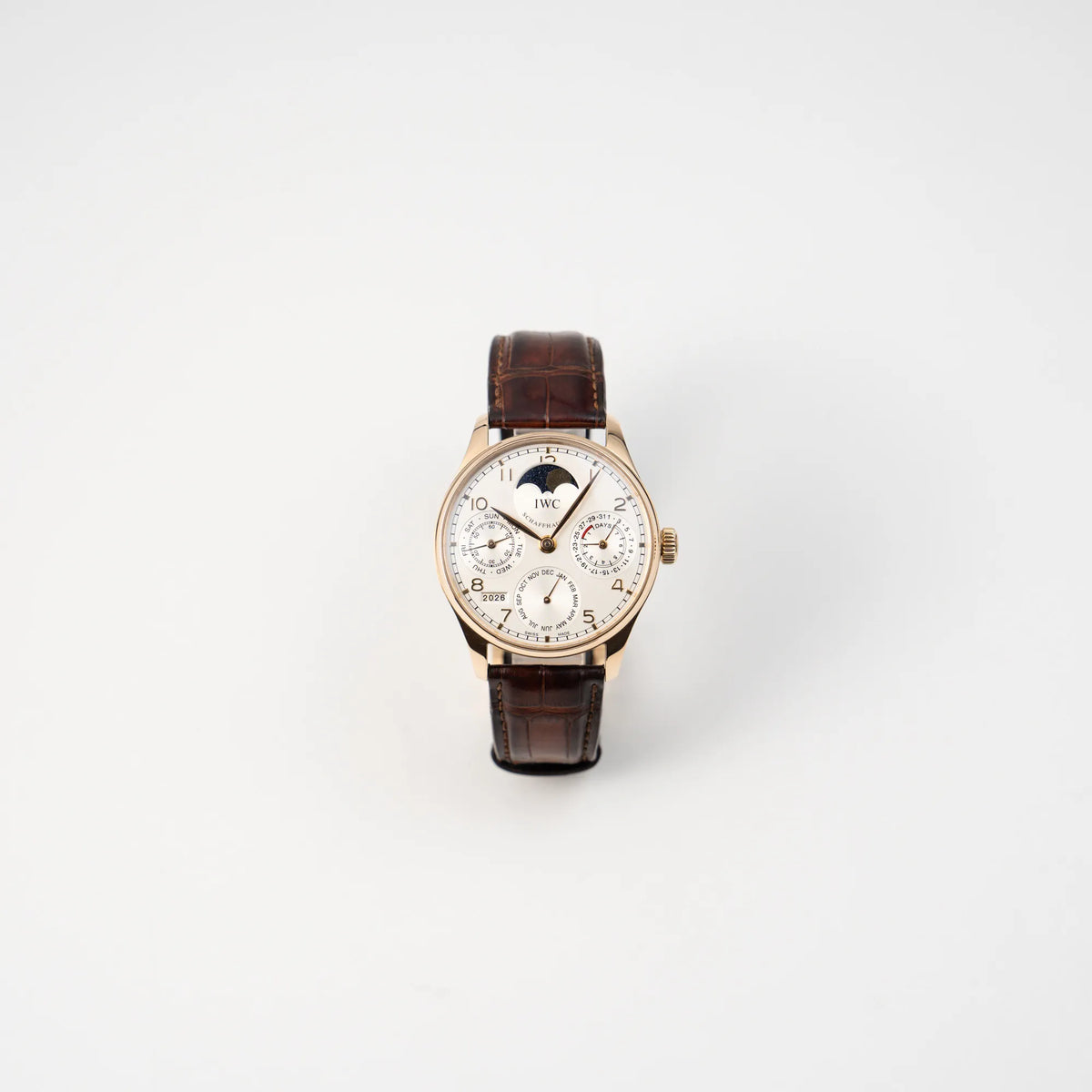 Frontale Ansicht des Portugieser Ewiger Kalender IW502213 von IWC in einem 42mm-Rosegold-Gehäuse am braunem IWC Lederband mit einem sanften weißem Zifferblatt
