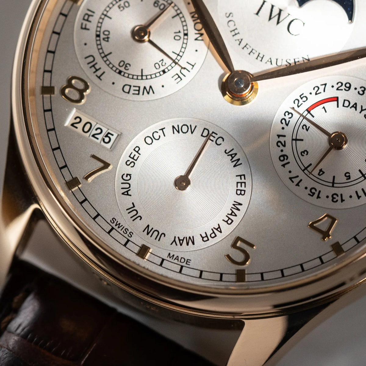 Makroaufnahme dr Monatsanzeige des Portugieser Ewiger Kalender IW502213 von IWC in einem 42mm-Rosegold-Gehäuse am braunem IWC Lederband mit einem sanften weißem Zifferblatt