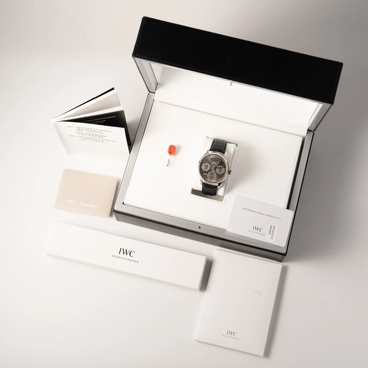 Lieferumfang zugehörig zu dem IWC Portugieser Ewiger Kalender IW502307 mit 44m Weißgold-Gehäuse und anthrazit-farbenem Zifferblatt, betsehend aus Box mit Umkarton, Papieren, Booklets und Scheibe für den Perpetual Calender