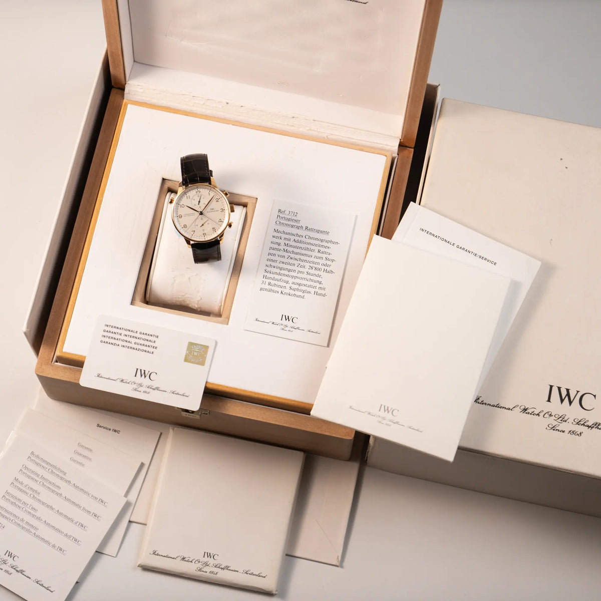 Lieferumfang zu dem IWC Portugieser Rattrapante Doppel-Chronograph IW3712 aus 18k Roségold mit weißem Zifferblatt am braunen Lederband, betsehend aus originaler Box mit Umkarton, Garantiekarte (=Papiere) und allen Booklets