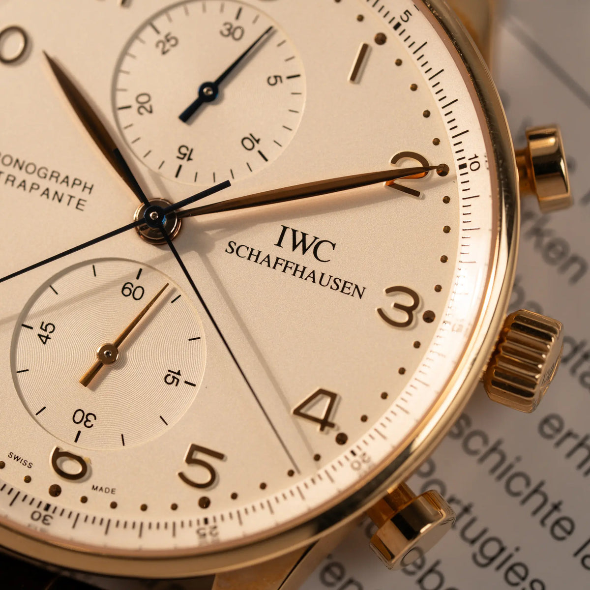 Makroaufnahme des IWC Schasffhausen Logos bei drei Uhr von dem IWC Portugieser Rattrapante Doppel-Chronograph IW3712 aus 18k Roségold mit weißem Zifferblatt am braunen Lederband