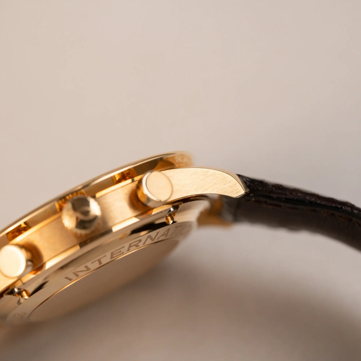 Produktfotografie des IWC Portugieser Rattrapante Doppel-Chronograph IW3712 aus 18k Roségold mit weißem Zifferblatt am braunen Lederband zeigt einen Bandanstoß im Topzustand