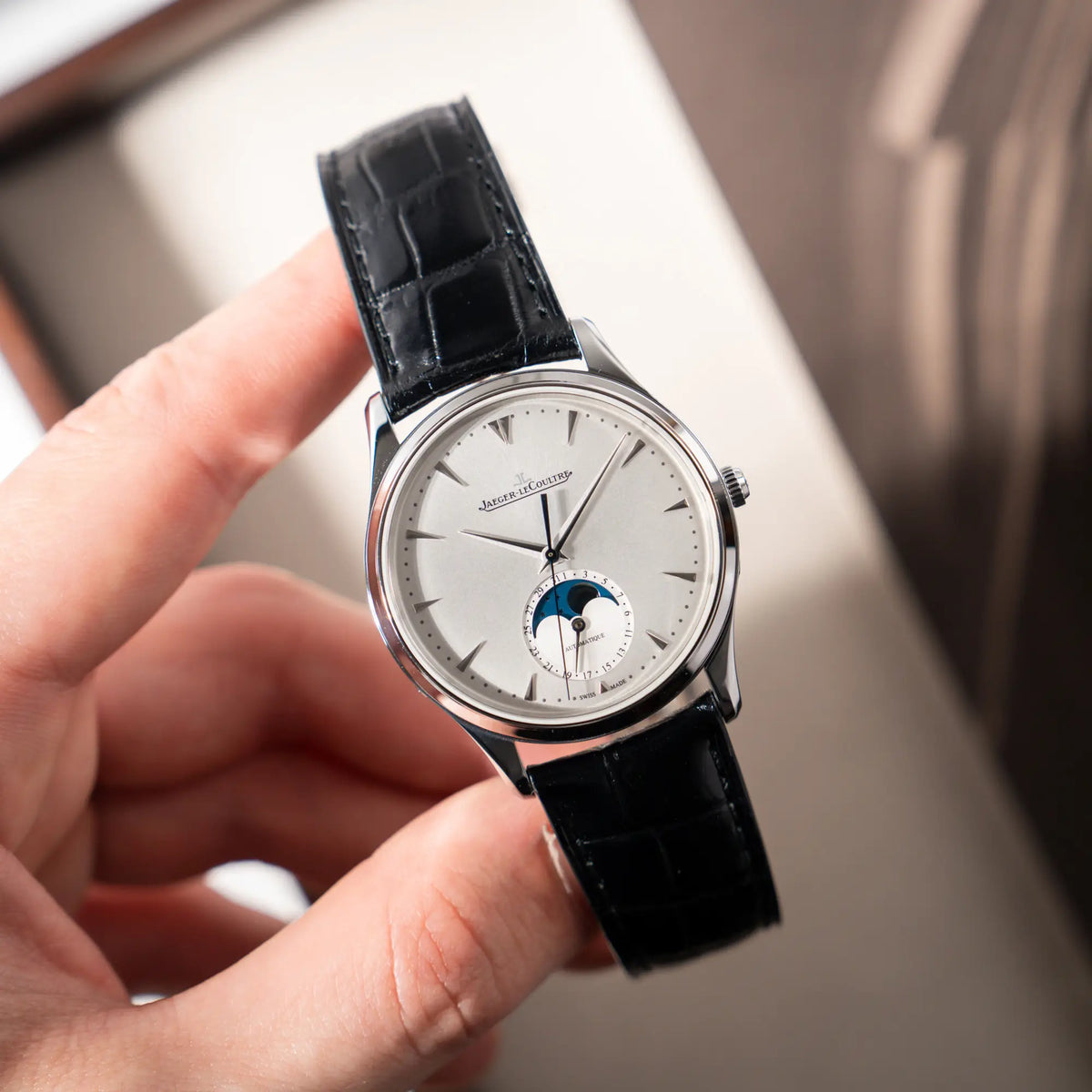Mann präsentiert die Jaeger-LeCoultre Master Ultra Thin mit Mondphase der Referenz 176.8.64.S mit weiß-silbernem Zifferblatt