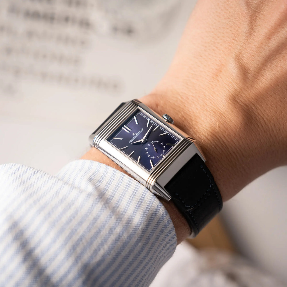 Wristshot mit der Jaeger-LeCoultre Reverso Duoface Q3988482 mit blauem Zifferblatt und weißem Night-and-Day-Zifferblatt am schwarzen Lederband an einem Männerhandgelenk