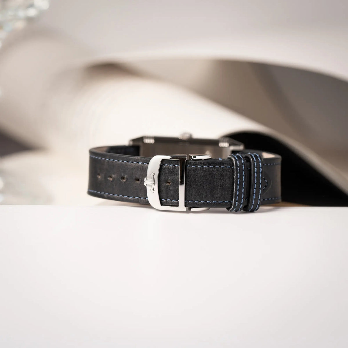 Produktfotografie der Stahl-Faltschliesse von der Jaeger-LeCoultre Reverso Duoface Q3988482 mit blauem Zifferblatt und weißem Night-and-Day-Zifferblatt am schwarzen Lederband