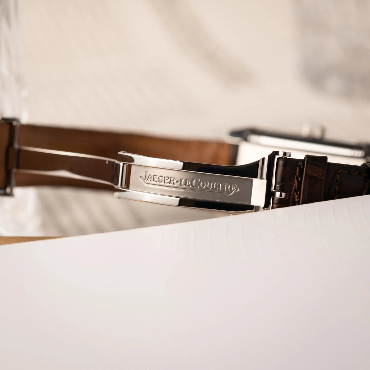 Detailaufnahme des JLC-Logos im Inneren der Faltschliesse von der Jaeger-LeCoultre Reverso Grande Date der Referenz 240.8.15 mit silberfarbenem Zifferblatt und Großdatums-Anzeige, kleiner Sekunde und Gangreserve-Anzeige am braunen Lederband