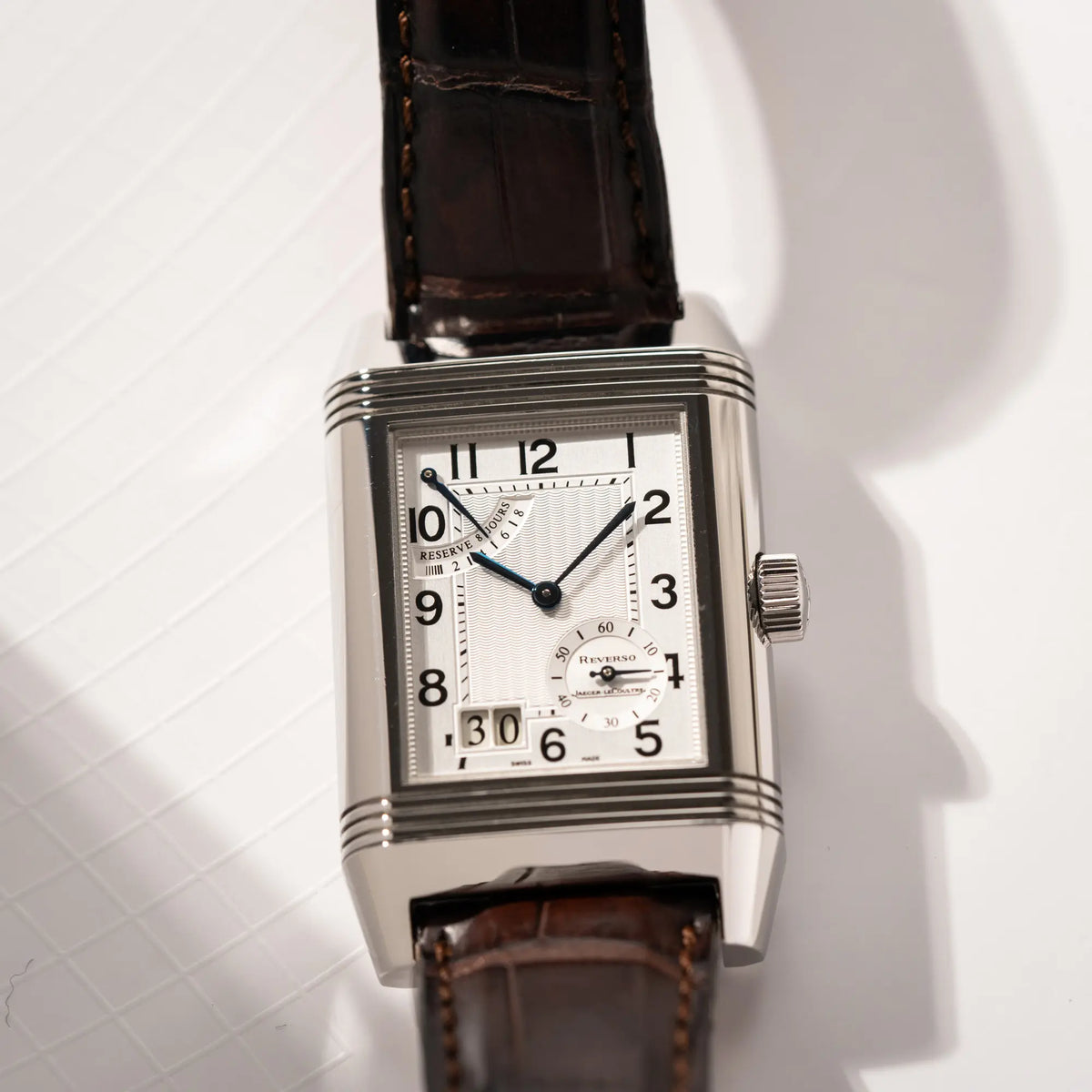 Detailaufnahme der Jaeger-LeCoultre Reverso Grande Date der Referenz 240.8.15 mit silberfarbenem Zifferblatt und Großdatums-Anzeige, kleiner Sekunde und Gangreserve-Anzeige am braunen Lederband