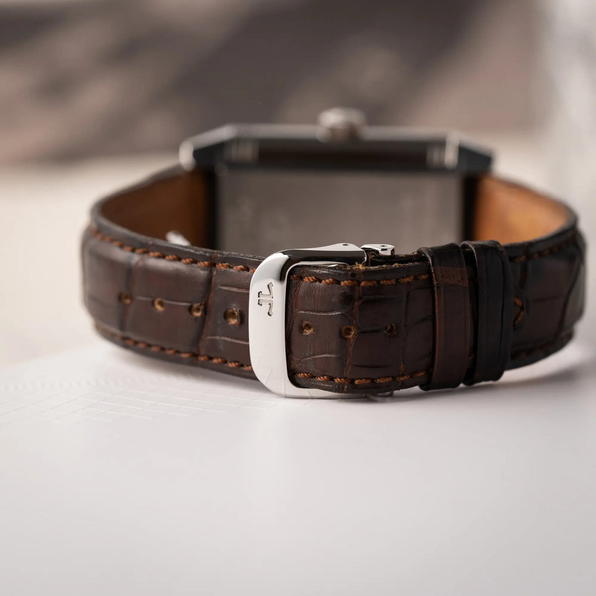 Produktfotografie der Jaeger-LeCoultre Reverso Grande Date der Referenz 240.8.15 mit silberfarbenem Zifferblatt und Großdatums-Anzeige, kleiner Sekunde und Gangreserve-Anzeige am braunen Lederband, zeigt die geschlossene Faltschliesse
