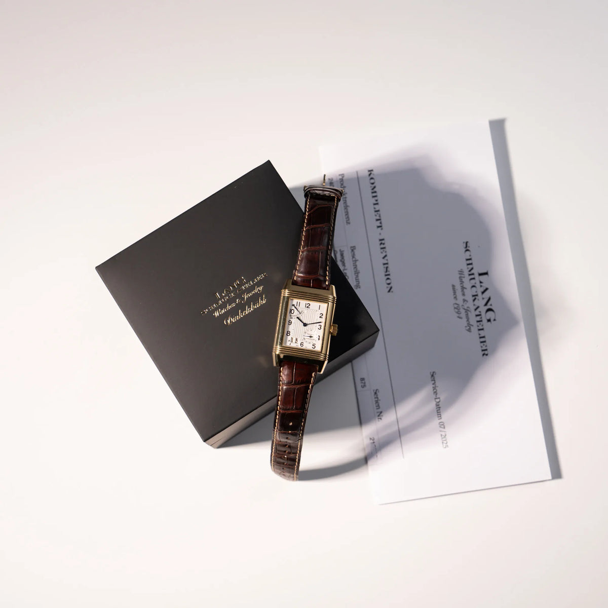 Lieferumfang der Jaeger-LeCoultre Reverso Grande Date der Referenz 240.1.15 mit einem Gelbgold-Gehäuse am braunen Lederband bestehend aus neutraler Box unseres Ateliers und Revisionsbeleg