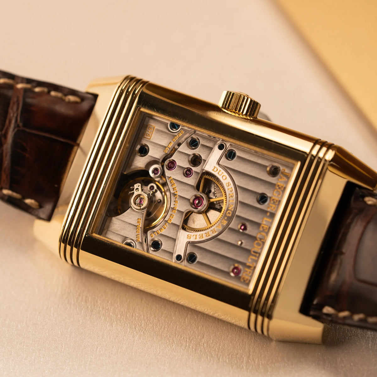Detailaufnahme des Uhrwerks durch das umgeklappte Revrso-Gehäuse der Jaeger-LeCoultre Reverso Grande Date der Referenz 240.1.15 mit einem Gelbgold-Gehäuse am braunen Lederband