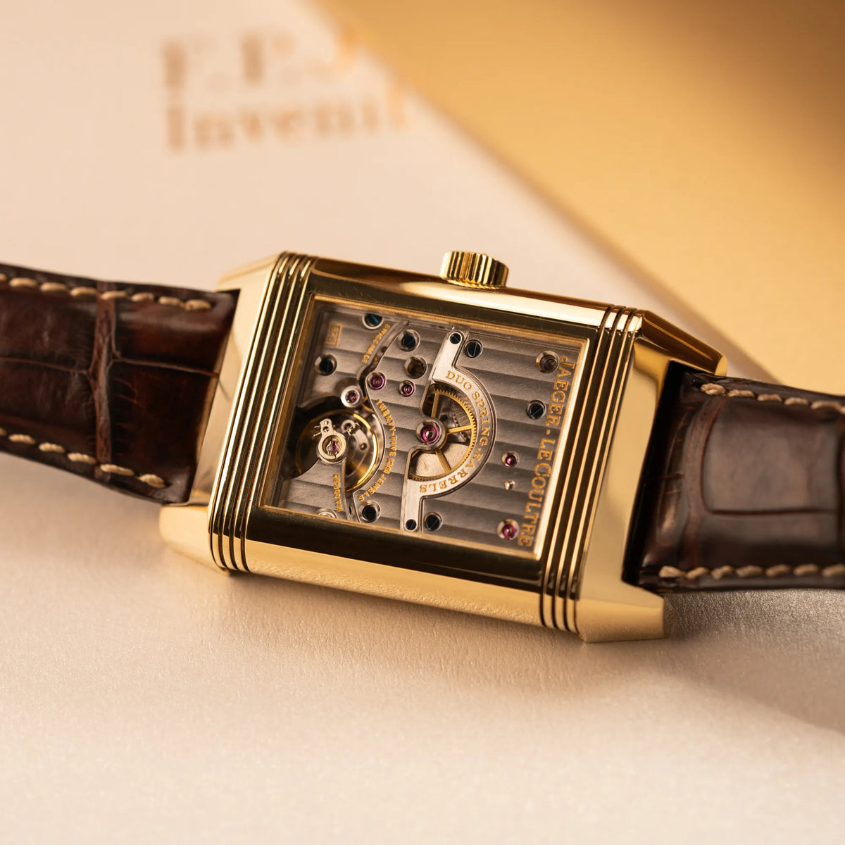 Detailaufnahme des Uhrenkopfes mit umgedrehten Reverso-Mechanismus der Jaeger-LeCoultre Reverso Grande Date der Referenz 240.1.15 mit einem Gelbgold-Gehäuse am braunen Lederband ermöglicht den Blick auf das Uhrwerk durch den Sichtboden aus Glas
