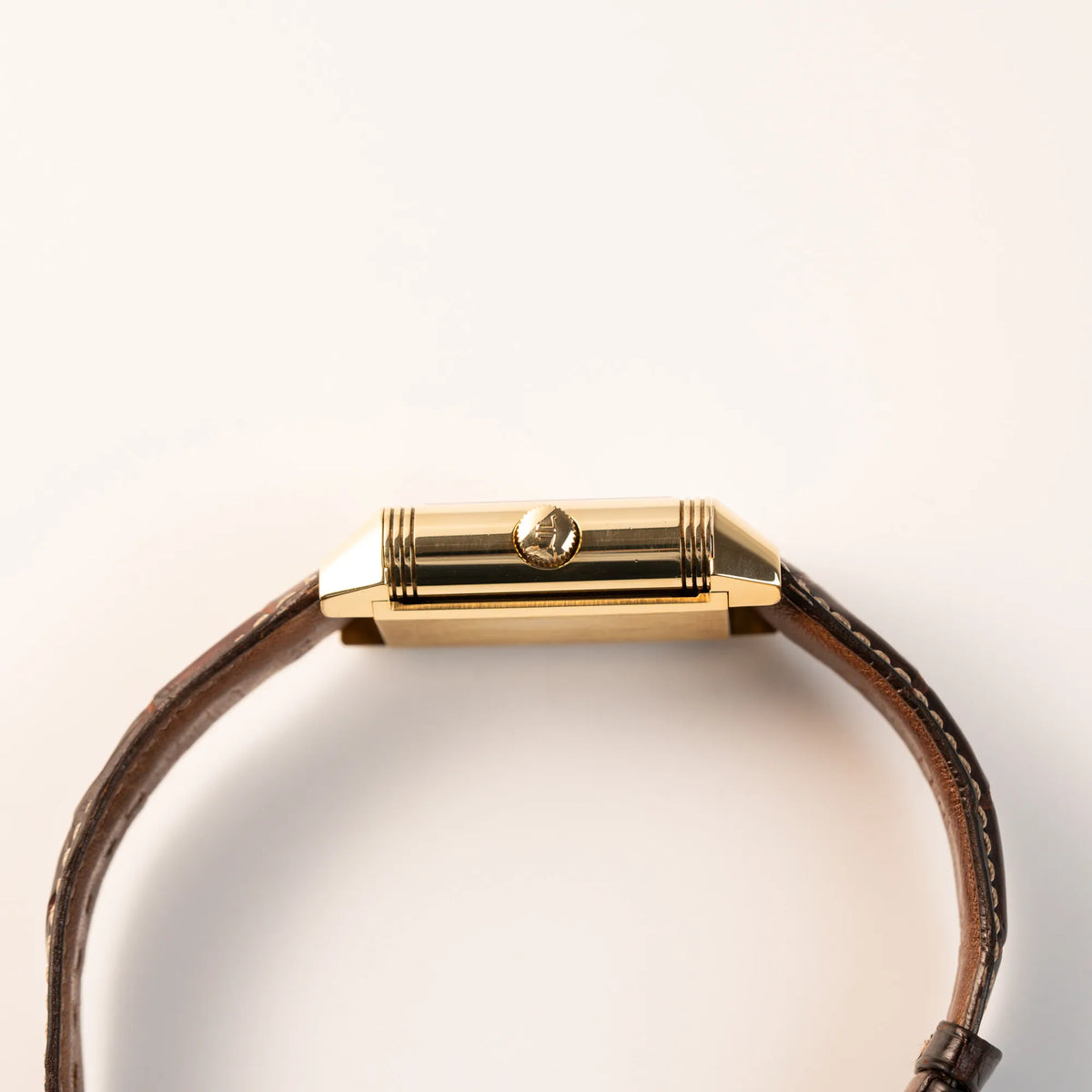 Seitliches Gehäuse der Jaeger-LeCoultre Reverso Grande Date der Referenz 240.1.15 mit einem Gelbgold-Gehäuse am braunen Lederband zeigt die Aufzugskrone