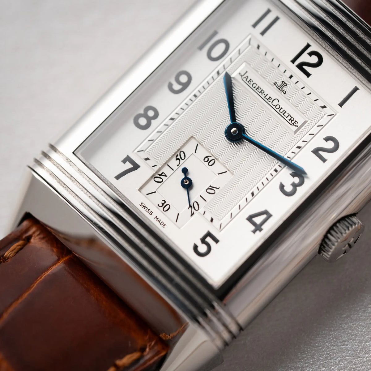 Makro-Aufnahme der Jaeger-LeCoultre Reverso Grande Taille der Referenz 270.8.62 mit einem teil-guillochiertem, silberfarbenem Zifferblatt an einem braunem Lederband mit Fokus auf der kleinen Sekunde bei 6 Uhr