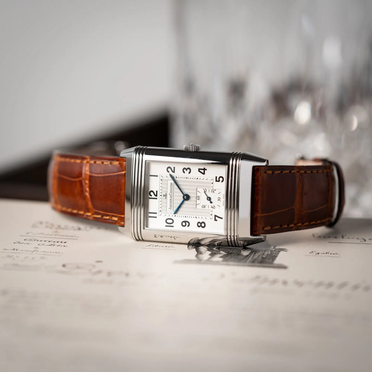 Produktfotografie seitlich auf dem Uhrengehäuse der Jaeger-LeCoultre Reverso Grande Taille der Referenz 270.8.62 mit einem teil-guillochiertem, silberfarbenem Zifferblatt an einem braunem Lederband
