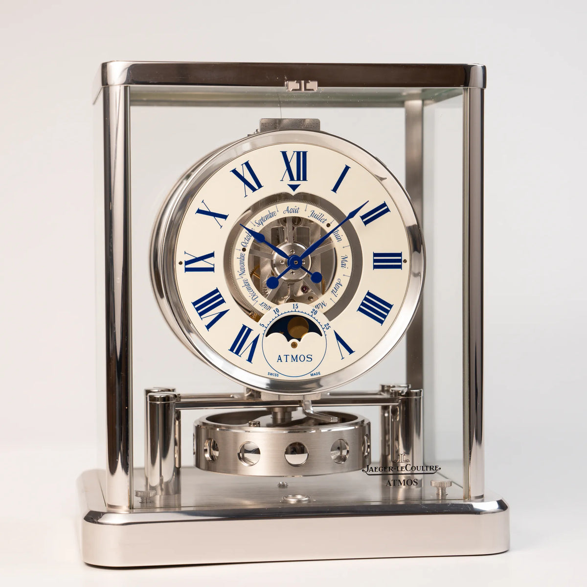 Produktfotografie der Jaeger-LeCoultre Atmos Mondphase Tischuhr in rhodiniertem Stahl mit weißem Zifferblatt und blauen römischen Indizes mit frontalem Blick auf die Tischuhr