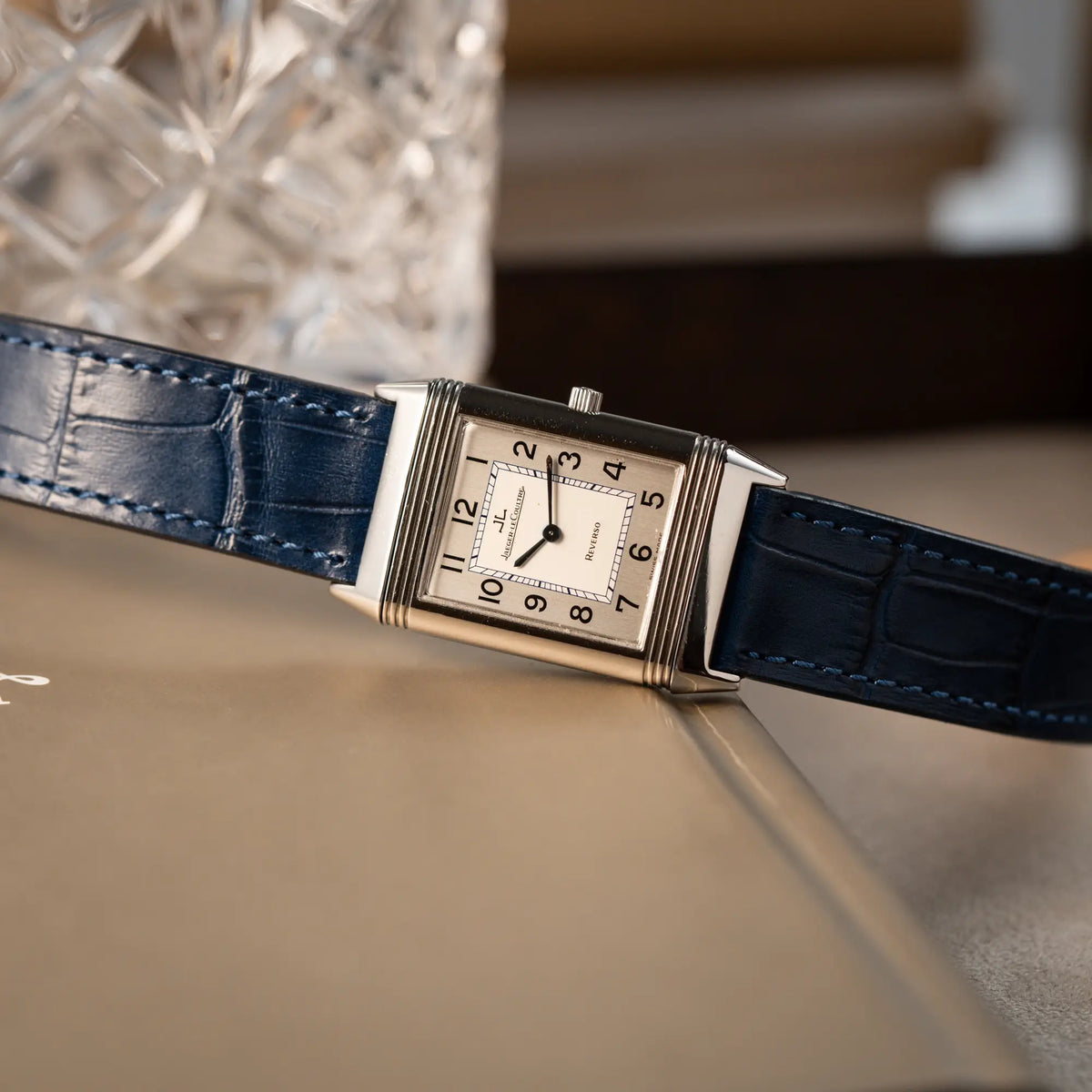 Prouktfotografie der seitlich auf dem Gehäuse liegenden Jaeger-LeCoultre Reverso Classique Medium 250.8.86 in Edelstahl an einem dunkelblauem Lederband