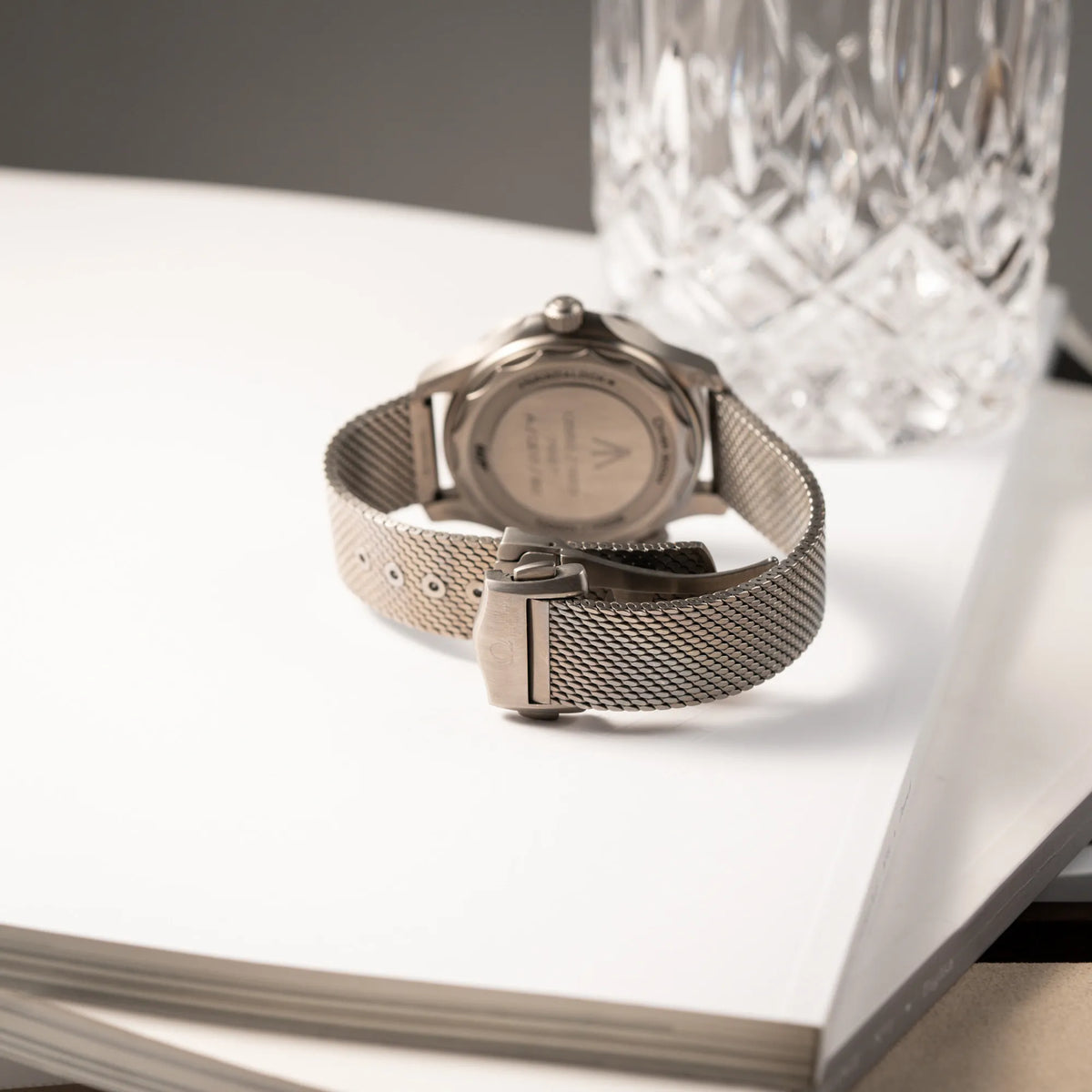 Produktfotografie der Omega Seamaster 300m Diver No Time To Die Limited Edition aus Titan mit braunem Zifferblatt zeigt das Milanese-Armband aus Titan und die geschlossene Titan-Faltschliesse