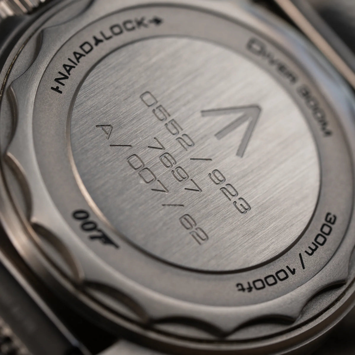 Detailaufnahme des Gehäusebodens der Omega Seamaster 300m Diver No Time To Die Limited Edition aus Titan mit braunem Zifferblatt