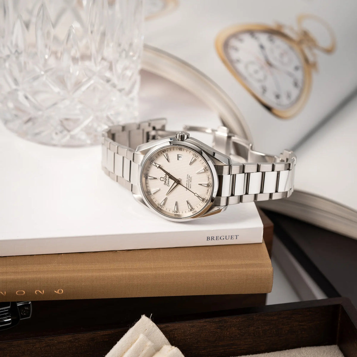 Produktfotografie der seitlich auf dem Gehäuse liegenden Omega Seamaster Aqua Terra 150M mit 41mm-Gehäuse und einem weißen Zifferblatt mit vertikal verlaufenden Linien