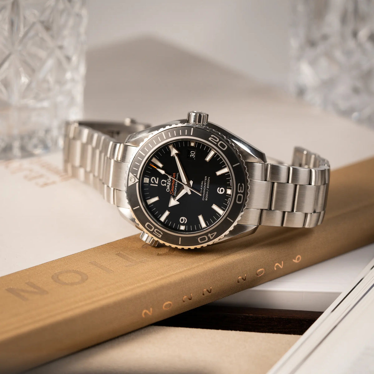 Produktfotografie der seitlich liegenden Omega Seamaster Planet Ocean 232.30.46.21.01.001 mit 45mm Gehäuse und schwarzem Zifferblatt mit orangen Details