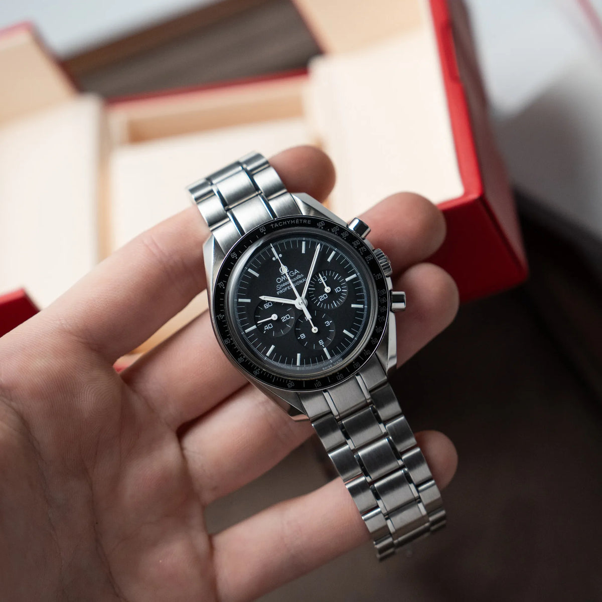 Mann hält die klassische Omega Speedmaster Professional Moonwatch mit Hesalitglas in seiner Hand