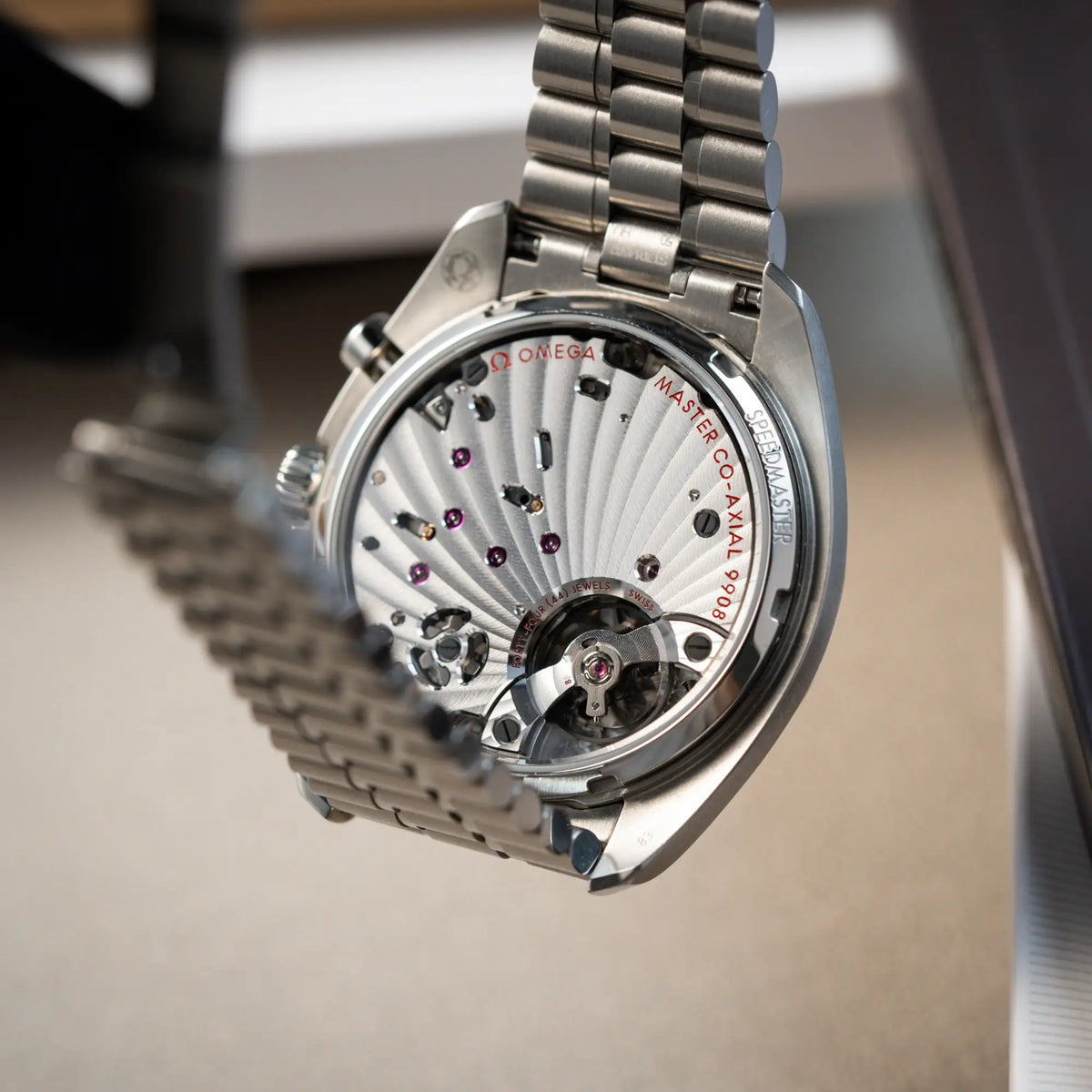 Produktfotografie der Omega Speedmaster Chronoscope aus Edelstahl mit blauem Zifferblatt und Pulsometerskala, sowie Telemeterskala zeigt den Gehäuseboden aus Glas mit Blick auf das Uhrwerk