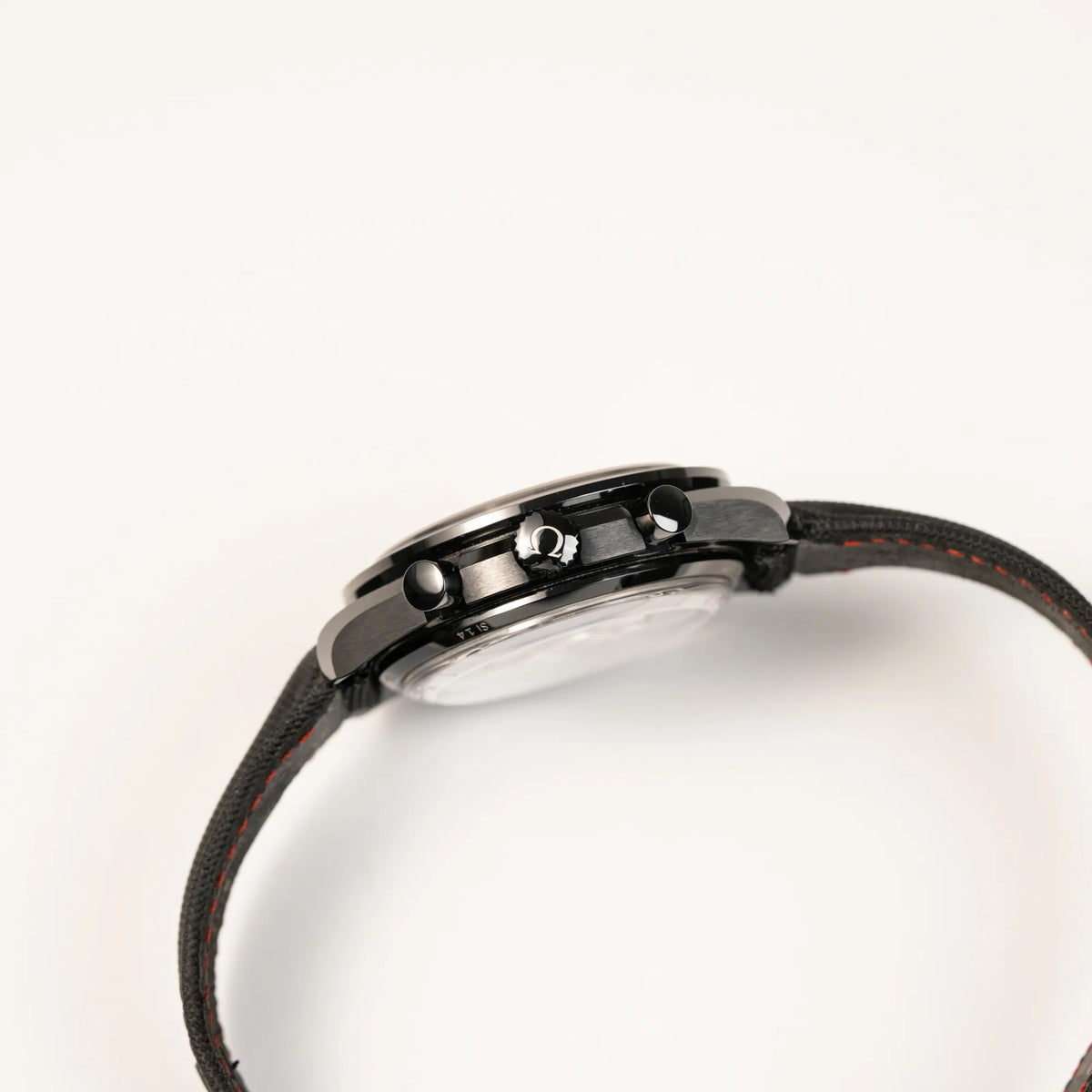 Seitliche Gehäuseflanke von dem Omega Speedmaster "Darkside of the Moon" Chronograph mit schwarzem Zifferblatt und aus schwarzer Keramik gefertigtem Gehäuse zeigt die Aufzugskrone mit Omega-Logo und die Chronograph-Drücker