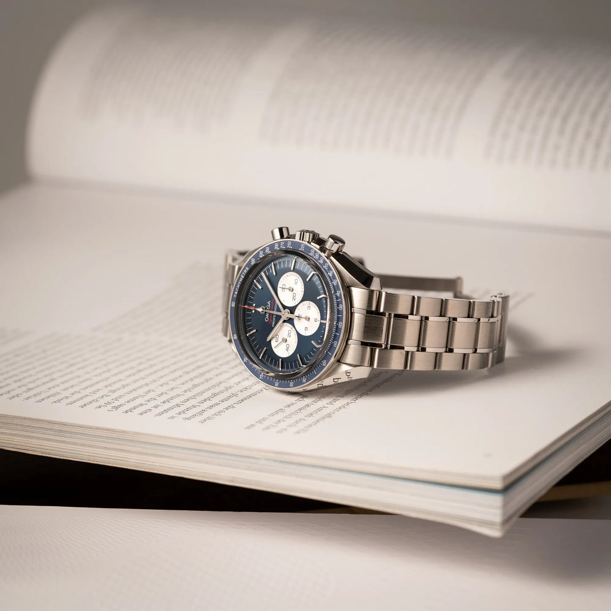 Omega Speedmaster Professional Moonwatch Tokyo Limited Edition mit blauem Zifferblatt und weißen Sub-Dials liegt auf einem Buch