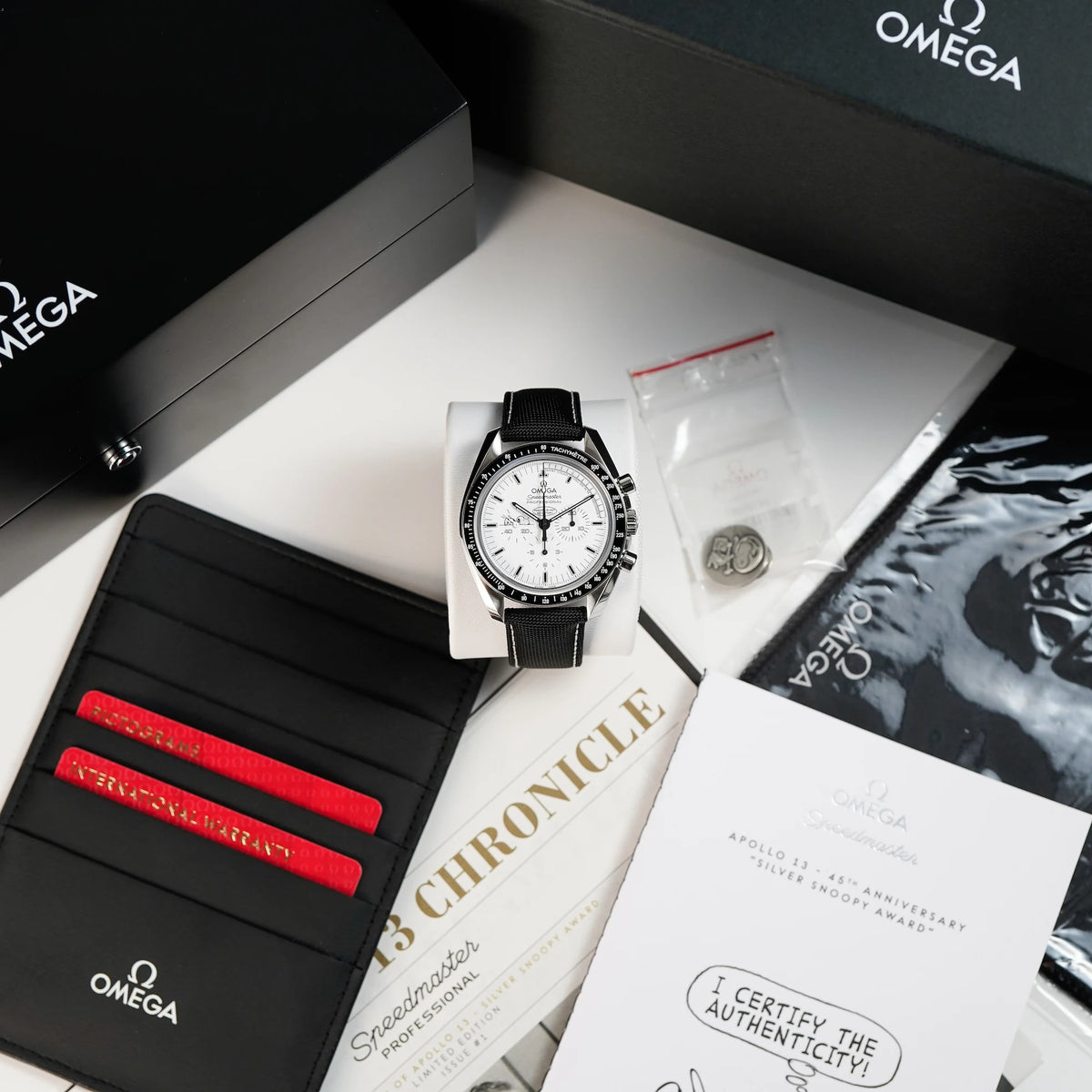 Omega Speedmaster Moonwatch Silver Snoopy mit dem weißen Zifferblatt zusammen mit dem Lieferumfang