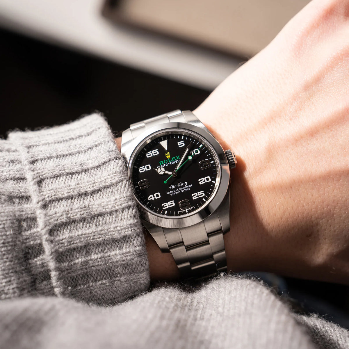 Mann trägt die Rolex Oyster Perpetual Air King 116900 mit 40mm Gehäuse und dem klassischen schwarzen Zifferblatt mit grünem Sekundenzeiger an seinem Handgelenk