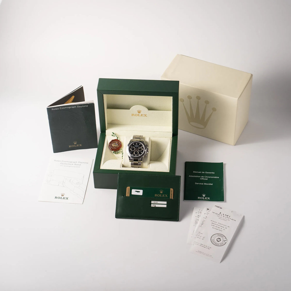 Lieferumfang zu der Rolex Cosmograph Daytona 116520 mit schwarzem Zifferblatt und der klassischen Edelstahl-Lünette vor Umstellung auf die Keramik-Lünette aus 2009, bestehend aus Box mit Ukarton, originaler Garantiekarte, Booklets, Dichtheitstest und Hangtag