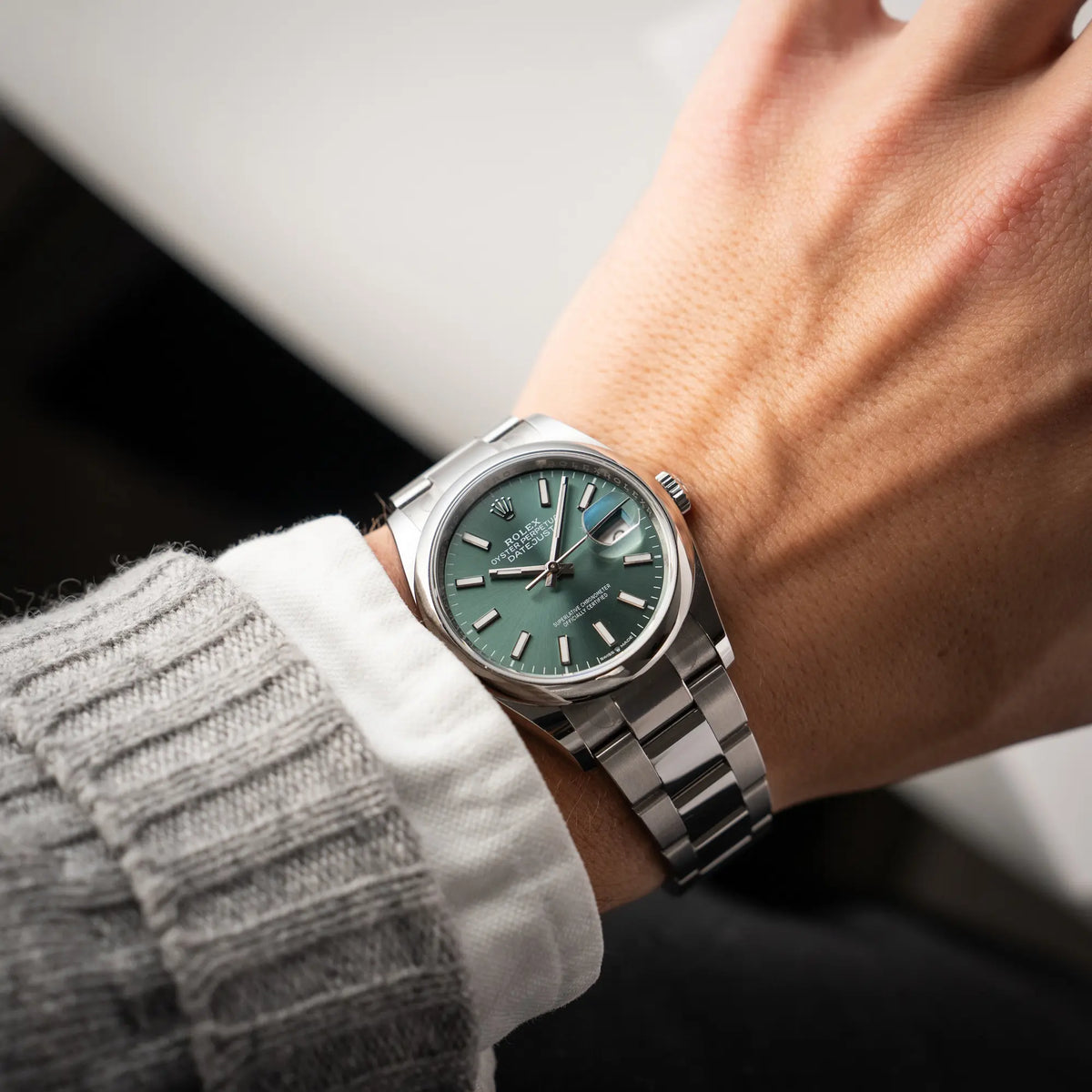 Mann trägt die mit Stickern teil-verklebte Rolex Datejust 36 der Referenz 126200 mit glatter Lünette am Oyster-Stahlband mit dem Mint-Green-Zifferblatt  an seinem Handgelenk