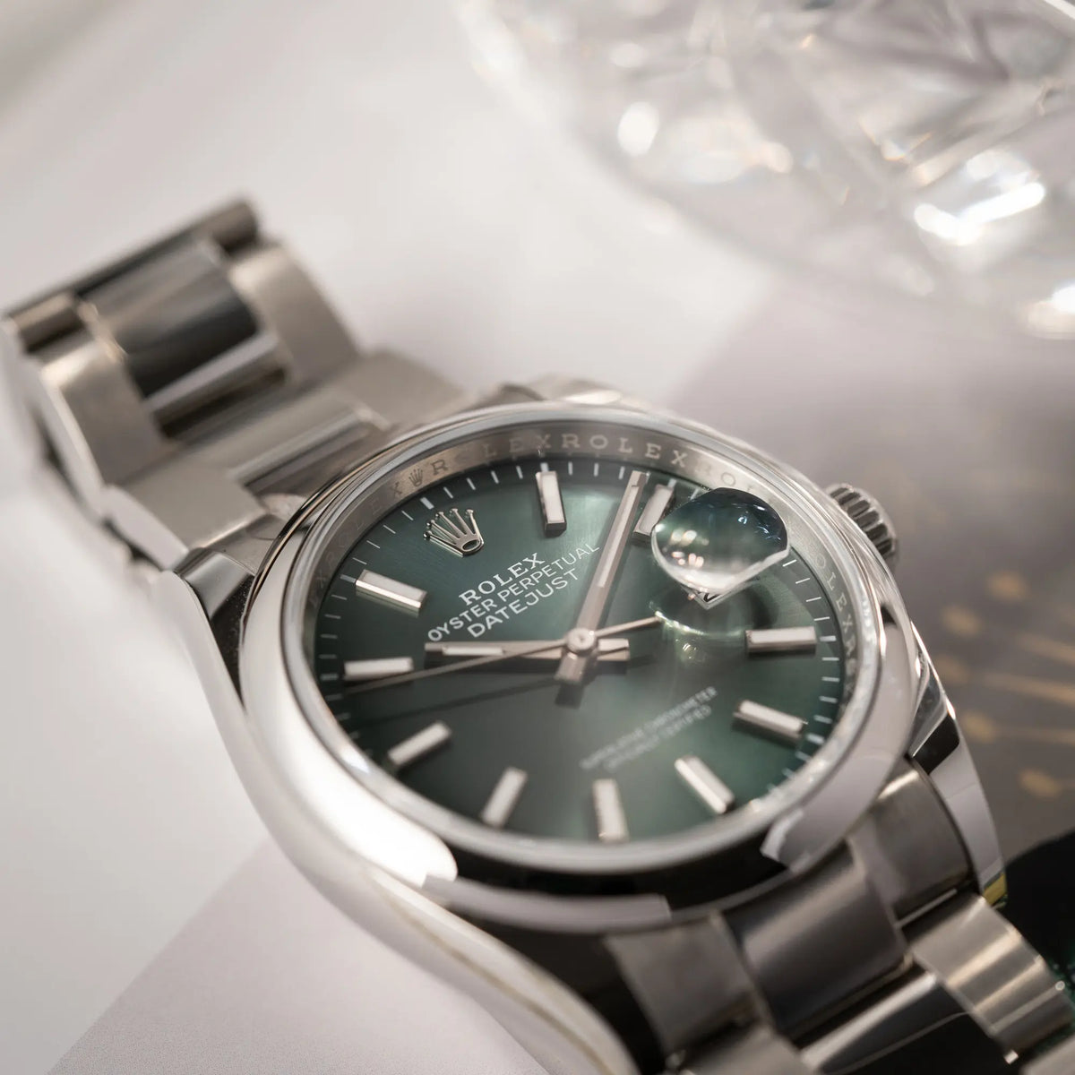 Produktfotografie der mit Stickern teil-verklebte Rolex Datejust 36 der Referenz 126200 mit glatter Lünette am Oyster-Stahlband mit dem Mint-Green-Zifferblatt, welche die Rolex-Krone bei 12 Uhr fokussiert