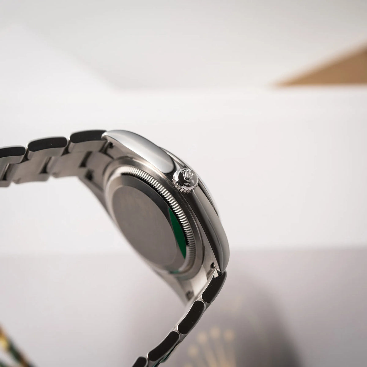 Seitliche Gehäuseflanke mit Blick auf die Aufzugskrone der mit Stickern teil-verklebte Rolex Datejust 36 der Referenz 126200 mit glatter Lünette am Oyster-Stahlband mit dem Mint-Green-Zifferblatt 
