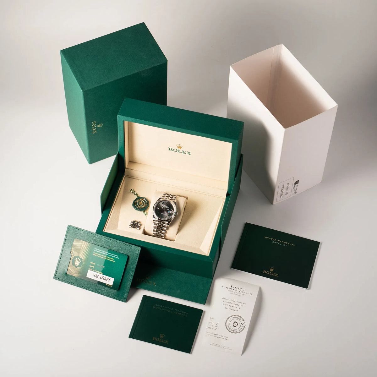 Lieferumfang zu der Rolex Datejust 36 Wimbledon der Referenz  126200 mit glatter Lünette, anthrazitfarbenem Zifferblatt und schwarz-grünen, römischen Indizes am Jubillee-Armband, bestehend aus Box mit Umkarton, allen Booklets, Hang-Tag und originaler Garantiekarte, sowie eine Wasserdichtheitstest