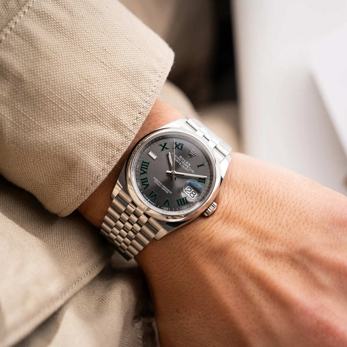 Mann trägt die x Rolex Datejust 36 Wimbledon der Referenz  126200 mit glatter Lünette, anthrazitfarbenem Zifferblatt und schwarz-grünen, römischen Indizes am Jubillee-Armband an seinem Handgelenk