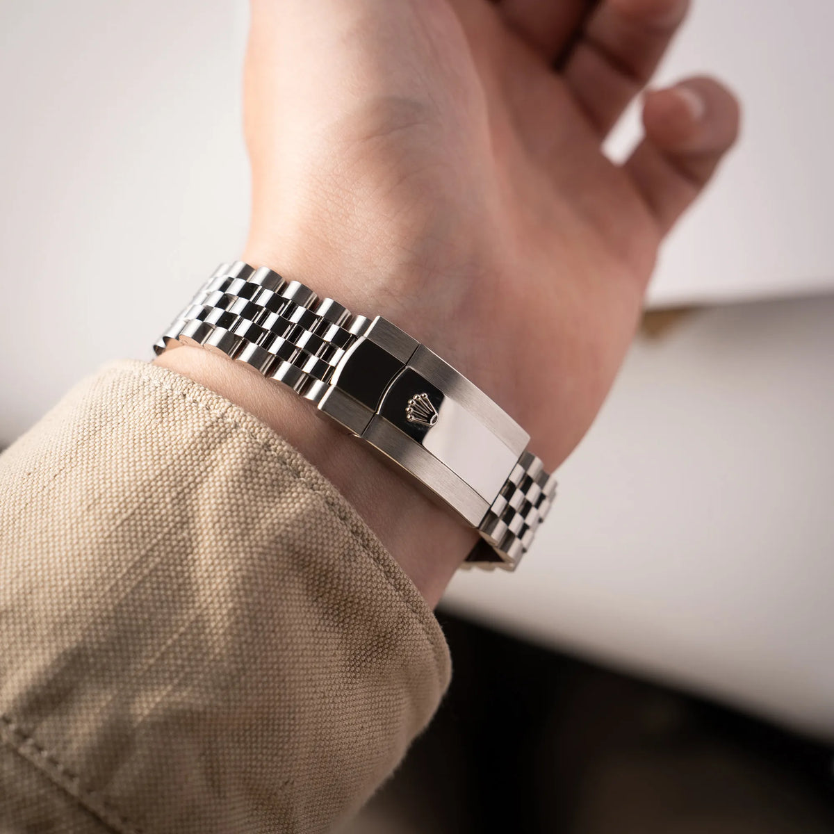 Mann trägt die  Rolex Datejust 36 Wimbledon der Referenz  126200 mit glatter Lünette, anthrazitfarbenem Zifferblatt und schwarz-grünen, römischen Indizes am Jubillee-Armband an seinem Handgelenk und präsentiert die Oyster-Schliesse