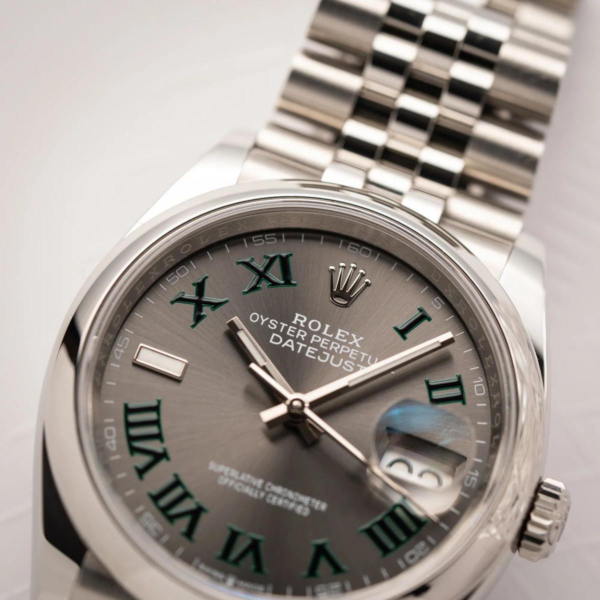 Detailaufnahme der  Rolex Datejust 36 Wimbledon der Referenz  126200 mit glatter Lünette, anthrazitfarbenem Zifferblatt und schwarz-grünen, römischen Indizes am Jubillee-Armband mit Fokus auf der Rolex-Krone auf 12 Uhr