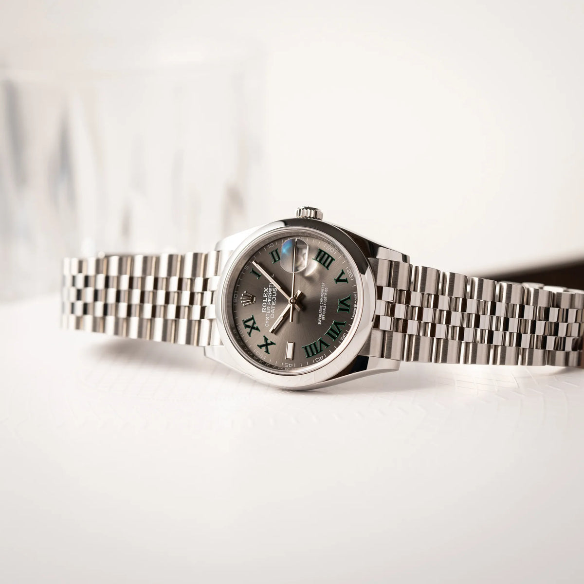 Seitlich auf dem Uhrengehäuse liegende Rolex Datejust 36 Wimbledon der Referenz 126200 mit glatter Lünette, anthrazitfarbenem Zifferblatt und schwarz-grünen, römischen Indizes am Jubillee-Armband