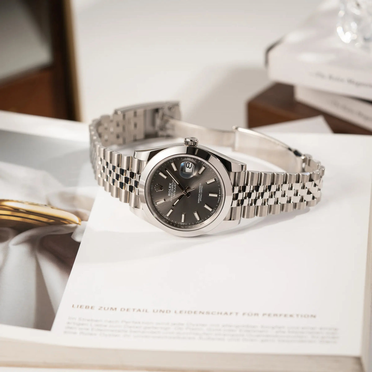 Rolex Datejust 41 der Referenz 126300 mit grauem Zifferblatt und glatter Lünette am Jubilee-Stahl-Armband liegt auf einem Magazin